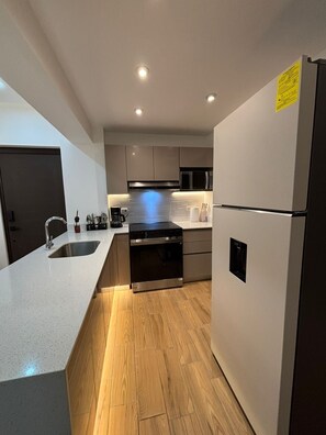 A modern kitchen with a stainless steel refrigerator, a built-in oven, a microwave, and a sink. - Apartamento moderno en Quetzaltenango (Quetzaltenango)