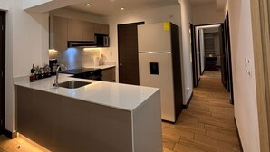 A modern kitchen with a central island, recessed lighting, and a wooden floor. - Apartamento moderno en Quetzaltenango (Quetzaltenango)