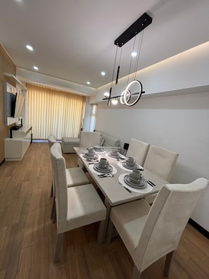 A modern dining area with a long table set for four, light-colored chairs, and a contemporary pendant light fixture. - Apartamento moderno en Quetzaltenango (Quetzaltenango)
