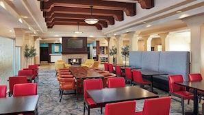 A hotel lobby with a fireplace, seating areas, and a TV screen. - Upscale King Room | 0.1 Miles to Six Flags | On-Site Restaurant & Lounge (Valencia)