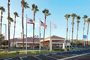 Ein Hotel mit Ziegeldach, Palmen und mehreren Flaggen, darunter die amerikanische Flagge.