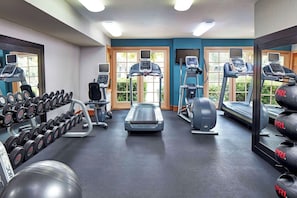 A gym with treadmills, dumbbells, and exercise balls.