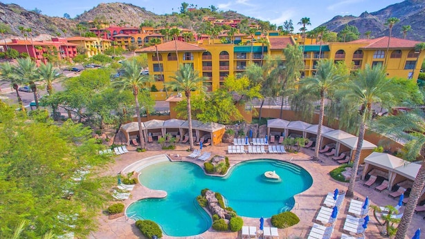 A resort with a central swimming pool, multiple lounge areas with sun loungers, and a backdrop of colorful buildings. - 1 King 1BR Suite, Hilton Phoenix Tapatio Cliffs, 7 Pools, Waterfall - 2 Units (Phoenix)