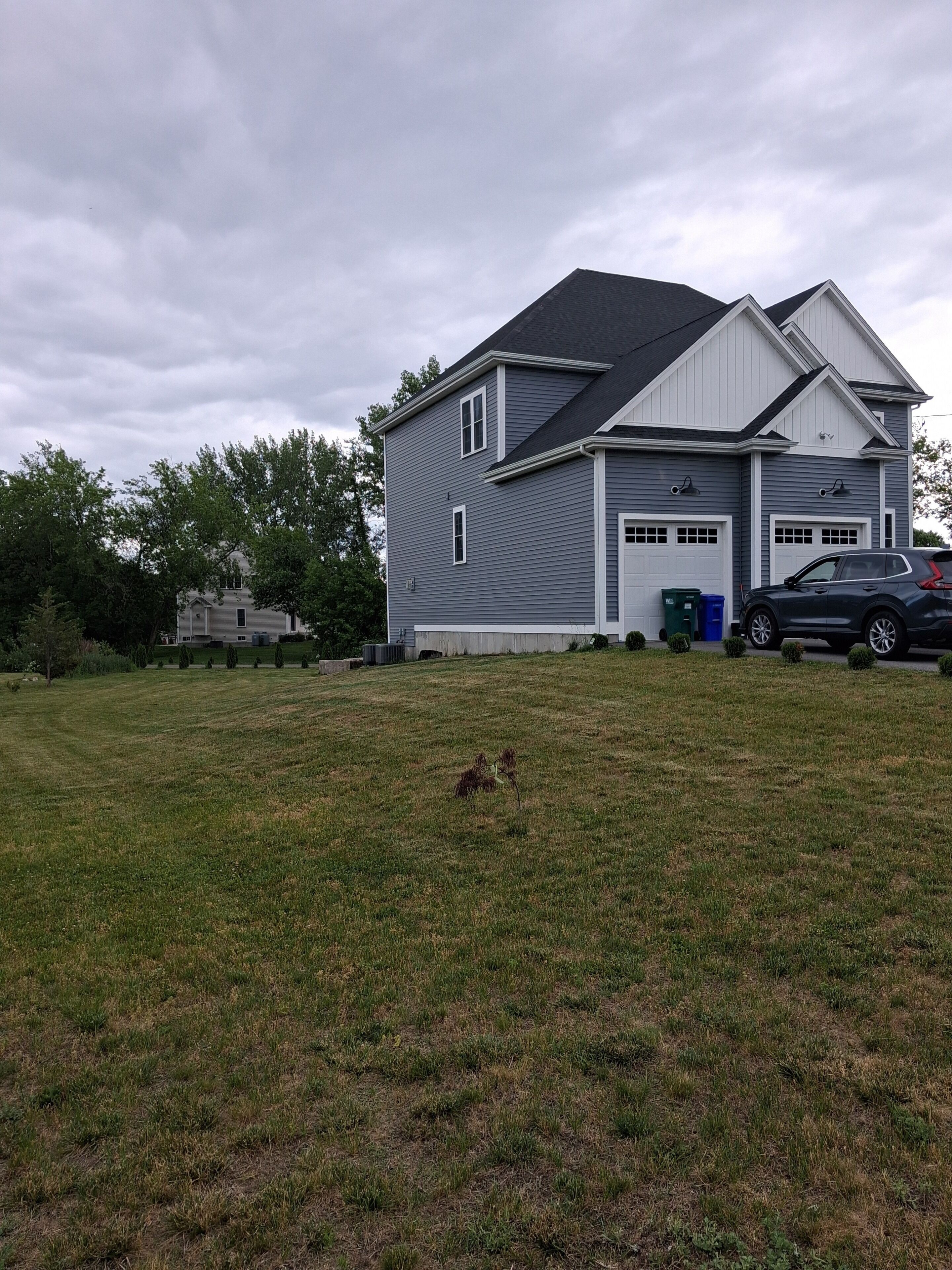 A two-story house with a garage, a lawn, and a parked SUV.