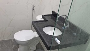 Casa de banho com sanita, lavatório e chuveiro.