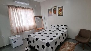Um quarto com uma cama, uma cadeira, um radiador e uma pequena mesa.