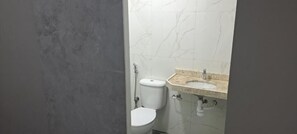 A bathroom with a toilet, sink, and marble wall. - HOSPEDARIA LENÇÓIS  (Barreirinhas)