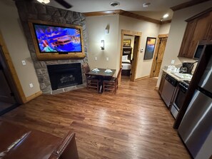A modern kitchen with a built-in oven, a refrigerator, and a dining area with a fireplace. - 4th July Family Vacation 2-bedroom Resort Cabin with Mountain view & Water Park (Gatlinburg)