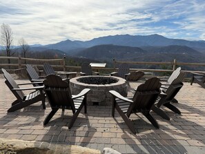 A fire pit surrounded by Adirondack chairs on a brick patio with a mountain view. - 4th July Family Vacation 2-bedroom Resort Cabin with Mountain view & Water Park (Gatlinburg)