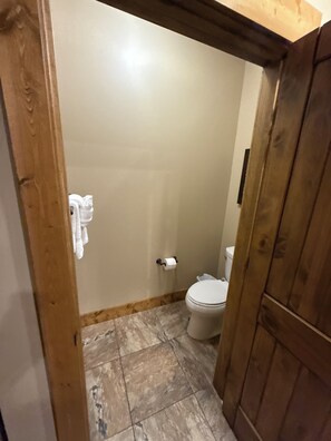 Een badkamer met een toilet, een handdoek aan de muur en een houten deuropening.