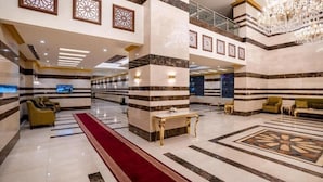 A spacious lobby with a red carpet, marble columns, and a chandelier. - Snood Al-dana (Makkah)