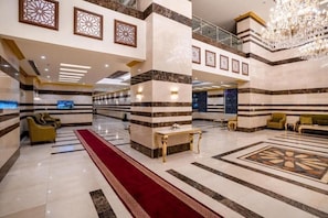A spacious lobby with a red carpet, marble columns, and a chandelier. - Snood Al-dana (Makkah)
