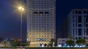 A tall hotel with multiple floors, a prominent entrance, and a well-lit facade. - Snood Al-dana (Makkah)