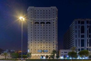 A tall hotel with multiple floors, a prominent entrance, and a well-lit facade. - Snood Al-dana (Makkah)
