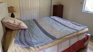 Ein Schlafzimmer mit einem Bett, einem Schminktisch, einer Lampe und einem Fenster.