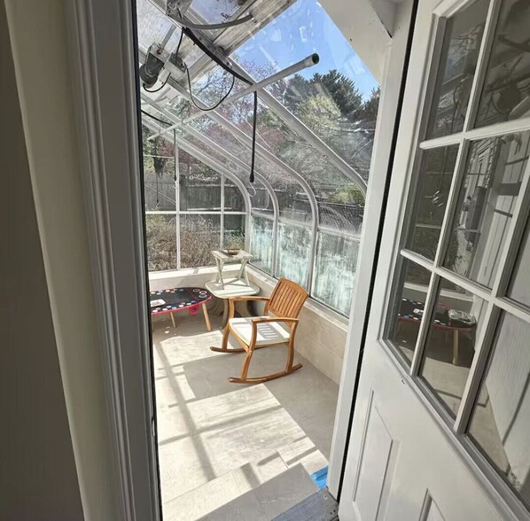 A conservatory with a table, chairs, and a small play area.