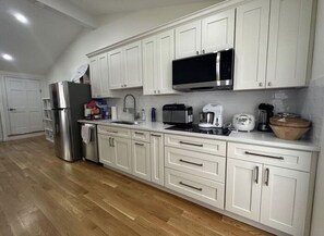 A kitchen with white cabinets, stainless steel appliances, and a wooden floor.