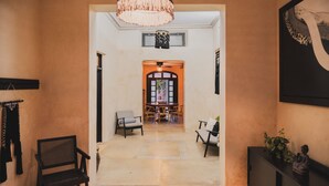 A hallway leading to a dining area with a chandelier, chairs, and a console table with a plant. - Charming Boutique Hotel Suite in the Heart of Merida (Mérida)