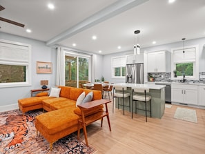 A modern kitchen with white cabinets, a stainless steel refrigerator, and a dining area with a wooden table and chairs. - Airy & Stylish New Build, 4 Bedrooms, 3.5 Bathrooms, Central to all of Asheville (Asheville)