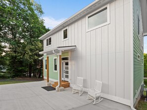 A two-story house with a porch, a door, and two rocking chairs. - Airy & Stylish New Build, 4 Bedrooms, 3.5 Bathrooms, Central to all of Asheville (Asheville)