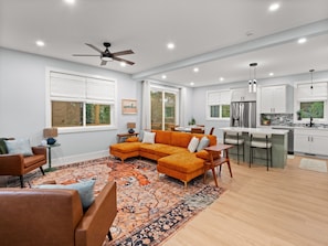 A modern living room with a sectional sofa, a dining area, and a kitchen with white cabinets and stainless steel appliances. - Airy & Stylish New Build, 4 Bedrooms, 3.5 Bathrooms, Central to all of Asheville (Asheville)