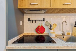 A kitchen with a black induction cooktop, a stainless steel sink, wooden cabinets, and a white tiled backsplash. - Casa do Bocage, By Home Match (Setúbal)
