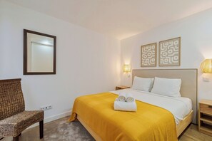 Ein Hotelzimmer mit Bett, Sessel, Spiegel und Wandbildern.