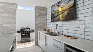 Eine moderne Küche mit integriertem Grill, großem Fenster und gefliestem Fliesenspiegel.