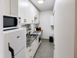A compact kitchen with white cabinets, a microwave, a gas stove, and a sink. - Apartment in Recoleta, close to all tourist attractions. (Buenos Aires)