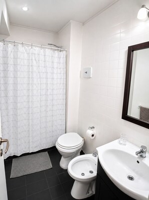 A bathroom with a toilet, bidet, sink, and shower curtain. - Apartment in Recoleta, close to all tourist attractions. (Buenos Aires)