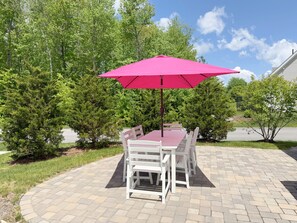 Een terras met een tafel, stoelen en een parasol, met een geplaveid vloertje.