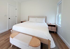 A bedroom with a bed, bedside tables, a bench, a window, and a door. - The Happy Nest - Sleeps 5 Near Kennebunk Beaches (Arundel)
