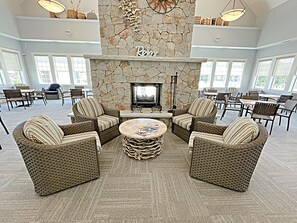 A spacious lounge area with wicker furniture, a stone fireplace, and large windows. - The Maine Happy-Nest / includes Kennebunk Beach Parking (Arundel)
