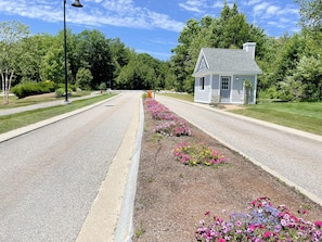 A residential street with a small house, a sidewalk, and flower beds. - The Maine Happy-Nest / includes Kennebunk Beach Parking (Arundel)