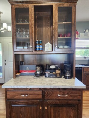 A kitchen with wooden cabinets, a coffee station, and a sign that says 'When life gives you lemons, trade them for coffee.' - Group Stays, Sleep 8-10, Near KC, Pet Friendly, 3 acres (Odessa)