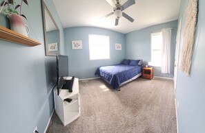 A bedroom with a bed, a ceiling fan, a TV, and a small table. - Group Stays, Sleep 8-10, Near KC, Pet Friendly, 3 acres (Odessa)