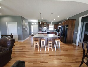 A spacious kitchen with a central island, wooden stools, and modern appliances.