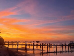 Een zonsondergang boven kalm water, met houten steigers die in het water steken.