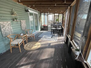Een overdekte veranda met houten stoelen, een klein tafeltje en een plant in pot.
