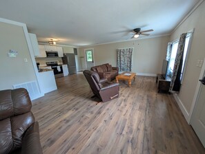 A living room with a brown leather sofa, a wooden coffee table, and a ceiling fan.