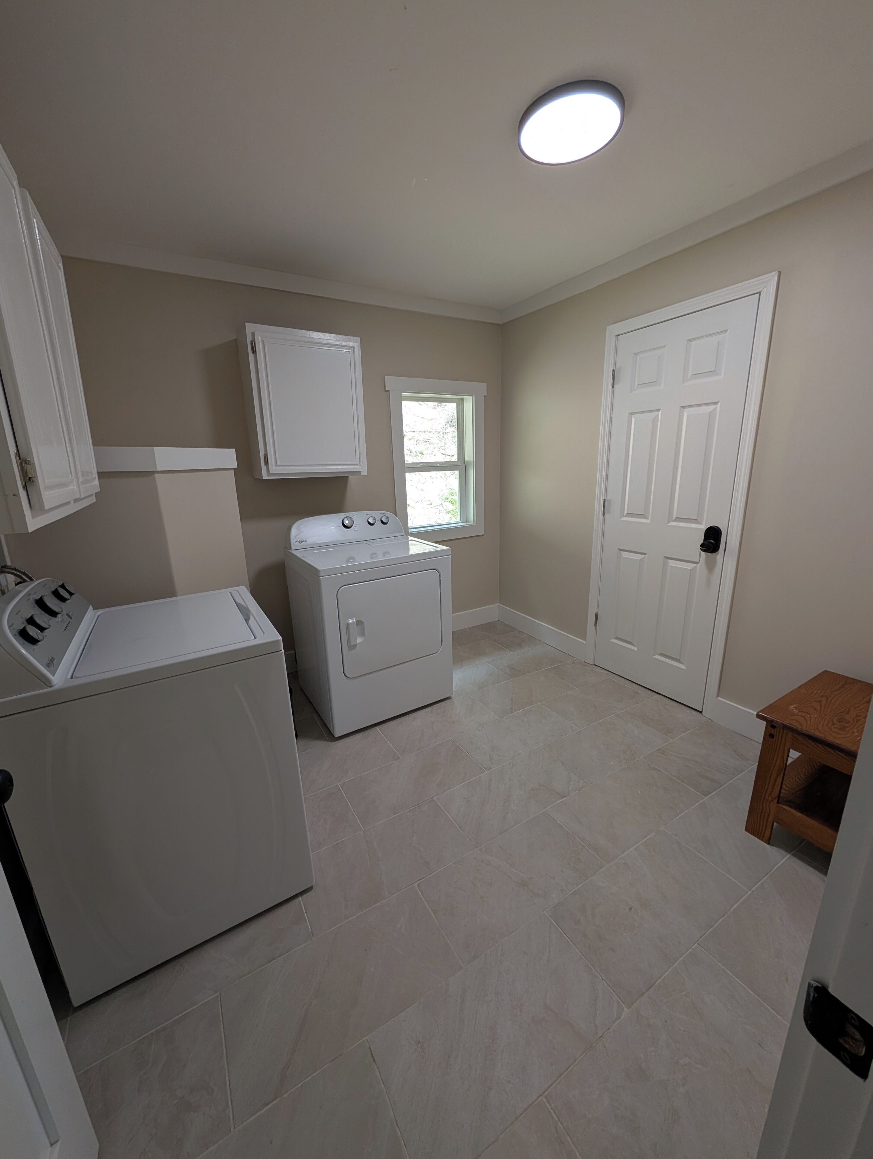 A laundry room with a washer and dryer, a window, and a door.