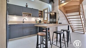 Een moderne keuken met donkere kastjes, een houten kookeiland en barstoelen.