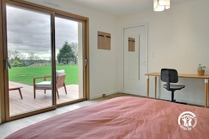 A bedroom with a large sliding glass door leading to a patio with a wooden deck and a lawn. - La Petite Casa de Silz (ARZAL)