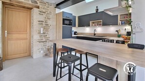Een moderne keuken met een stenen muur, een houten deur en een bar met krukken.