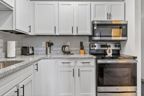 Una cocina con armarios blancos, microondas, tostadora y horno.