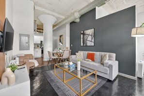 Een moderne woonkamer met een bank, een salontafel en een eethoek op de achtergrond.
