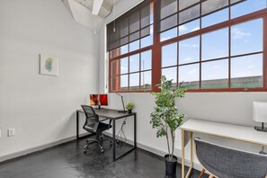 Un espacio de oficina moderno con un ventanal grande, un escritorio, una silla y una planta en maceta.