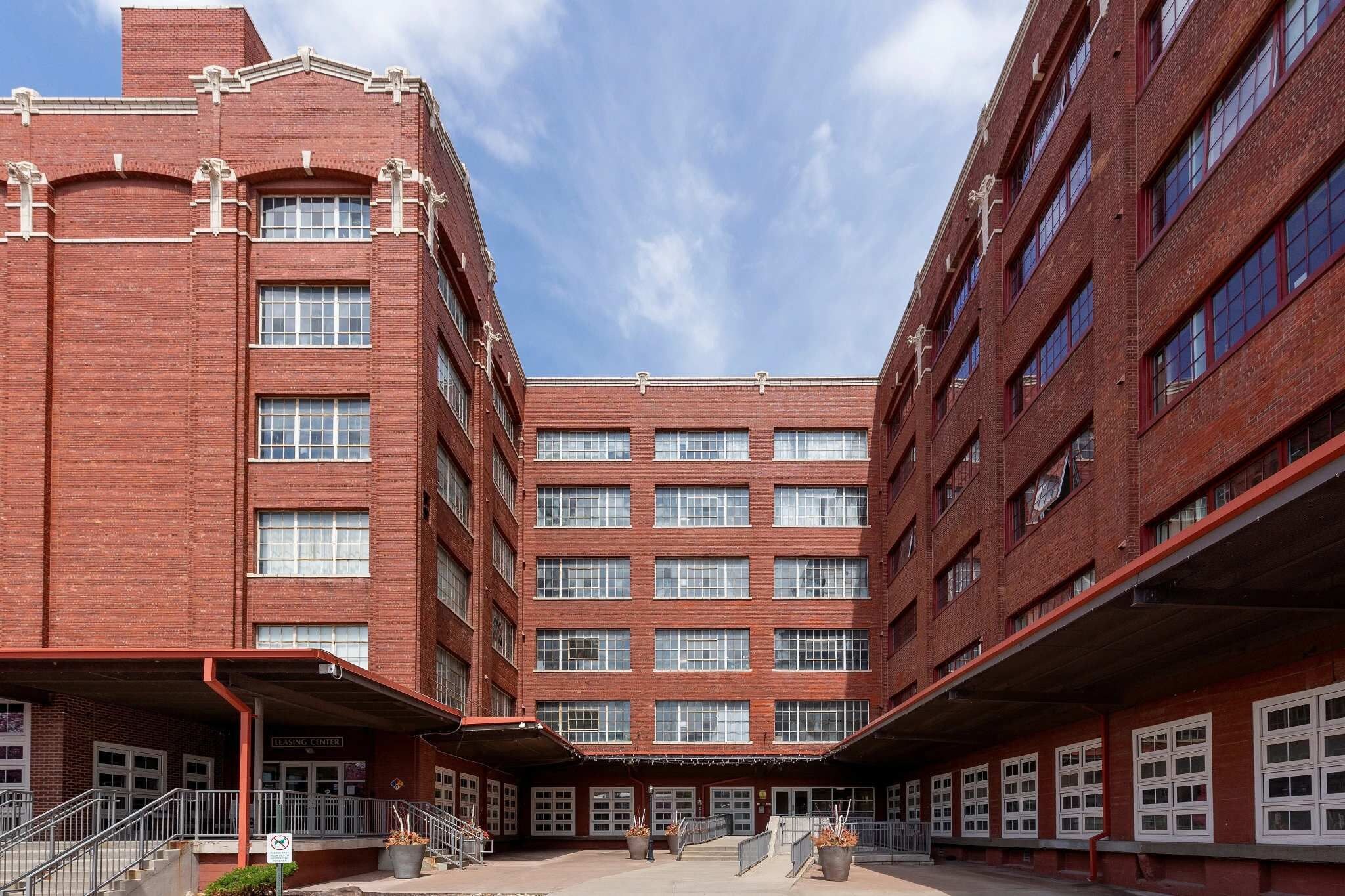 Een meerlaags bakstenen gebouw met een centrale binnenplaats, grote ramen en een bord met daarop 'Learning Center'.