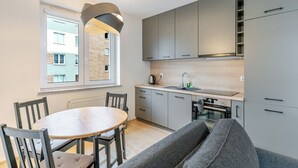 Una cucina moderna con mobili grigi, un tavolo rotondo in legno e un divano grigio.