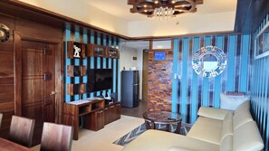 Ein modernes Wohnzimmer mit Fernseher, einer Holz-Unterhaltungseinrichtung, einer Couch und einer Wand mit Muster.